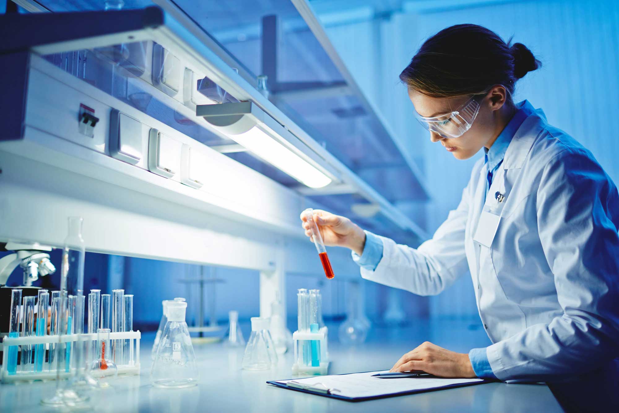 Woman in a lab coat holding the test tube in a laboratory